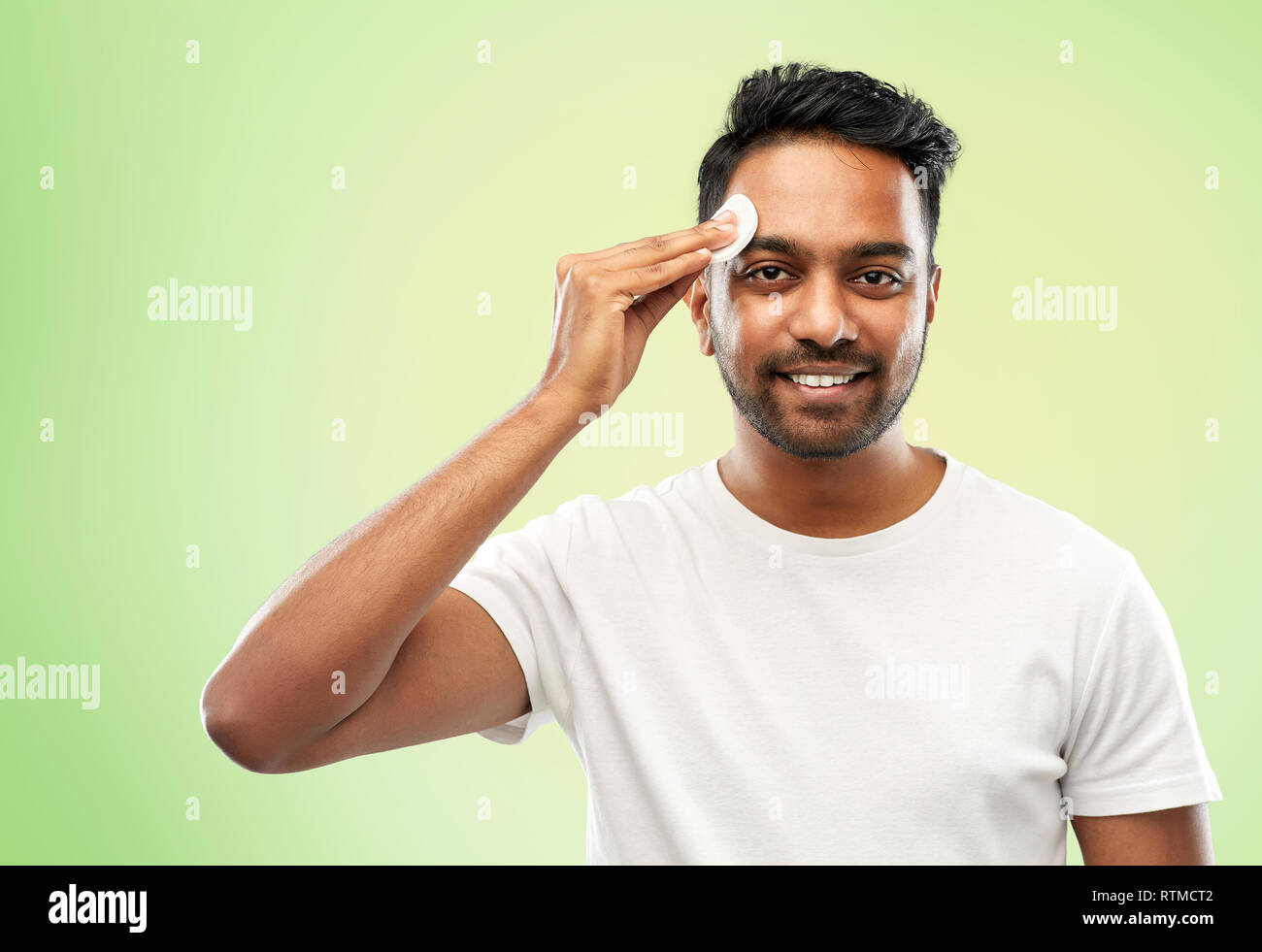 smiling indian man cleaning face with cotton pad Stock Photo Alamy