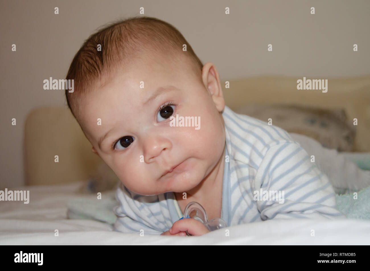 cute 4 months old baby boy having tummy time and making funny faces