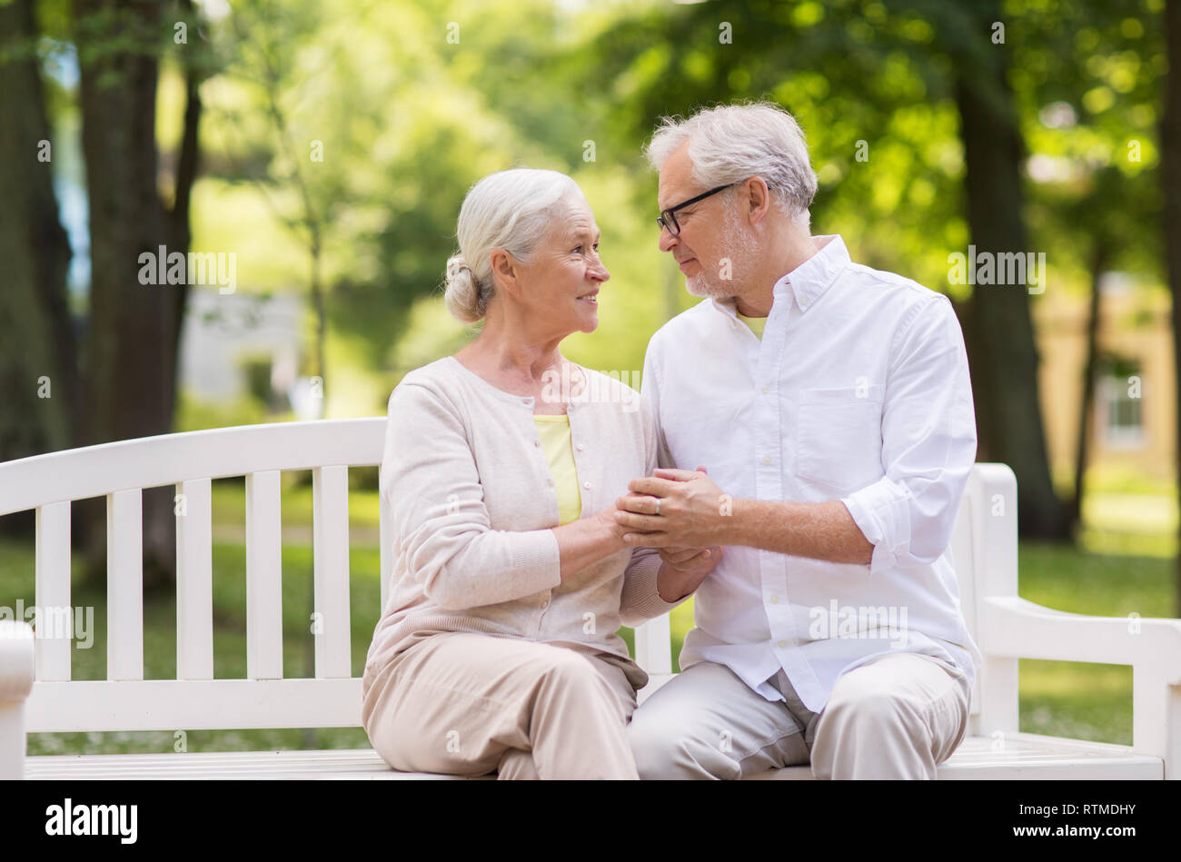 happy senior couple sitting on bench at park Stock Photo - Alamy