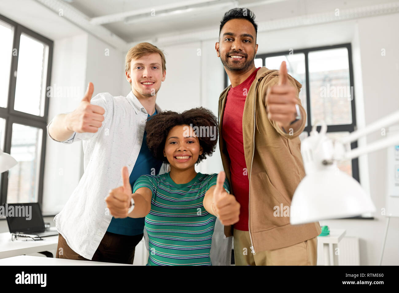 happy creative team showing thumbs up at office Stock Photo - Alamy