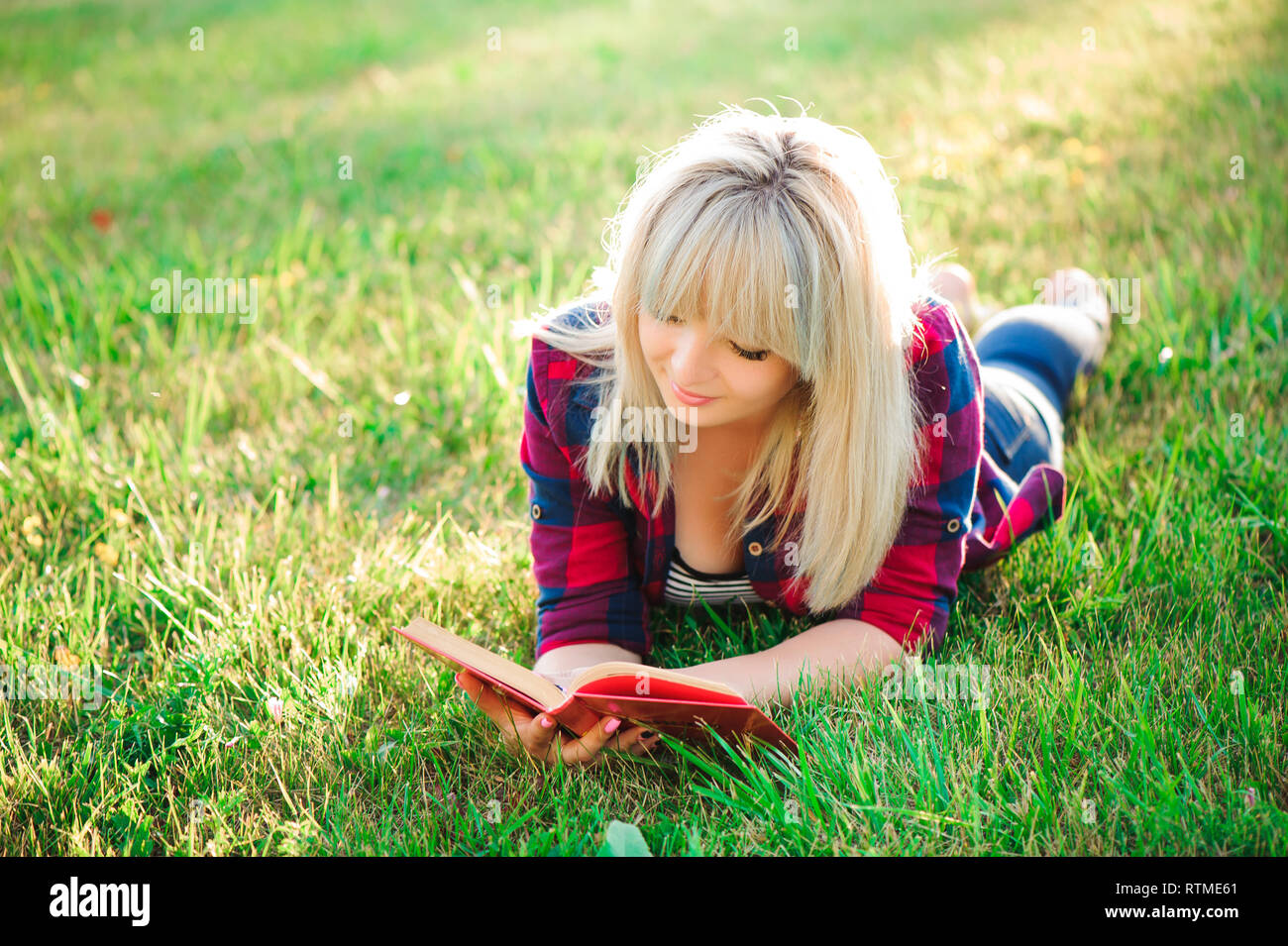 Young beautiful girl reading a book outdoor Stock Photo - Alamy