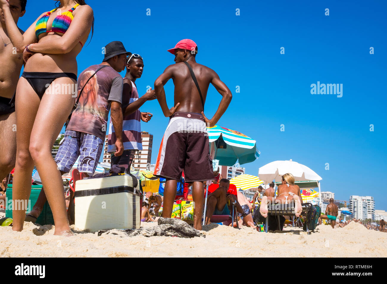 RIO DE JANEIRO - MARCH 15, 2015: A group of unlicensed Brazilian beach vendors stand together among beachgoers on the shore of Ipanema Beach. Stock Photo