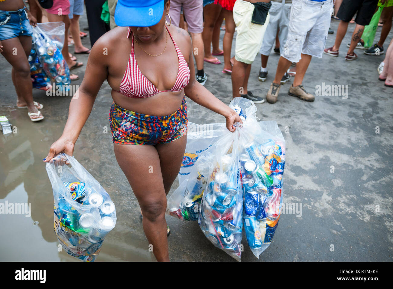 RIO DE JANEIRO - FEBRUARY 11, 2017: A Brazilian woman carries a collection of cans for recycling in the aftermath of an Ipanema Carnival street party. Stock Photo