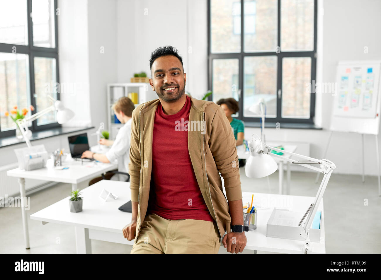 smiling indian man with smart watch at office Stock Photo