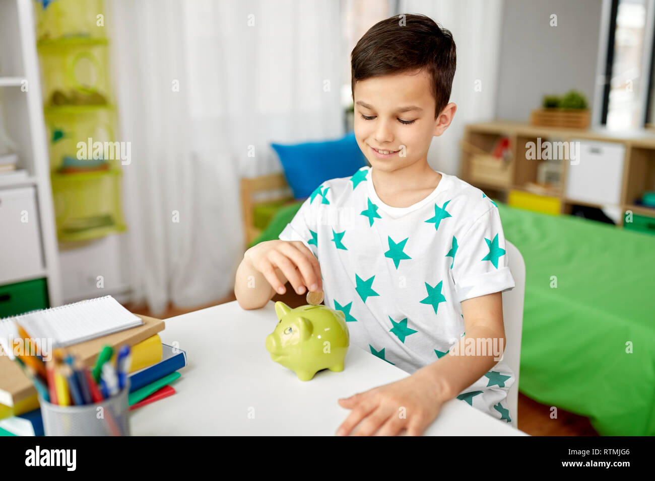 little boy putting coin into piggy bank at home Stock Photo - Alamy