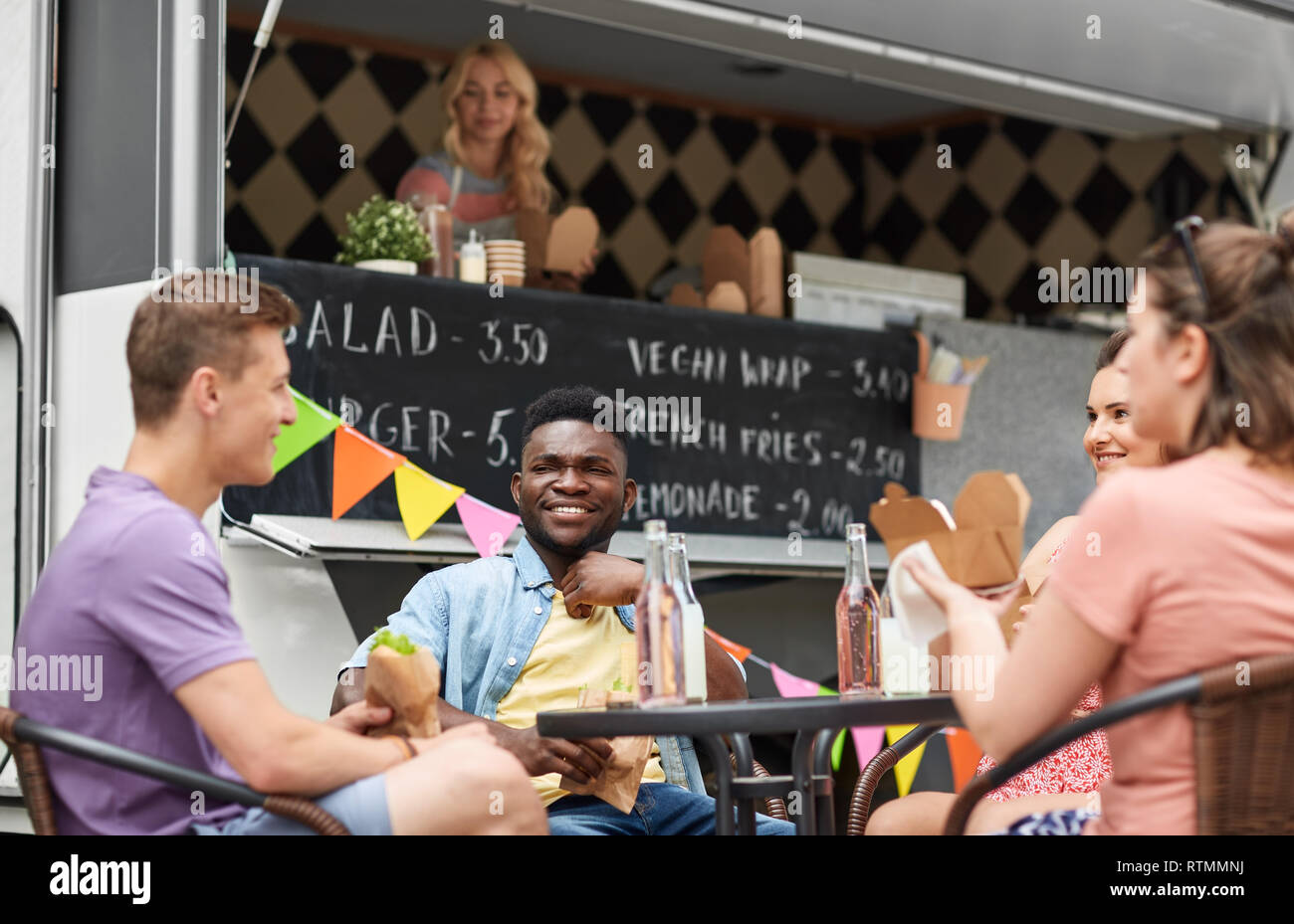 happy friends with drinks eating at food truck Stock Photo