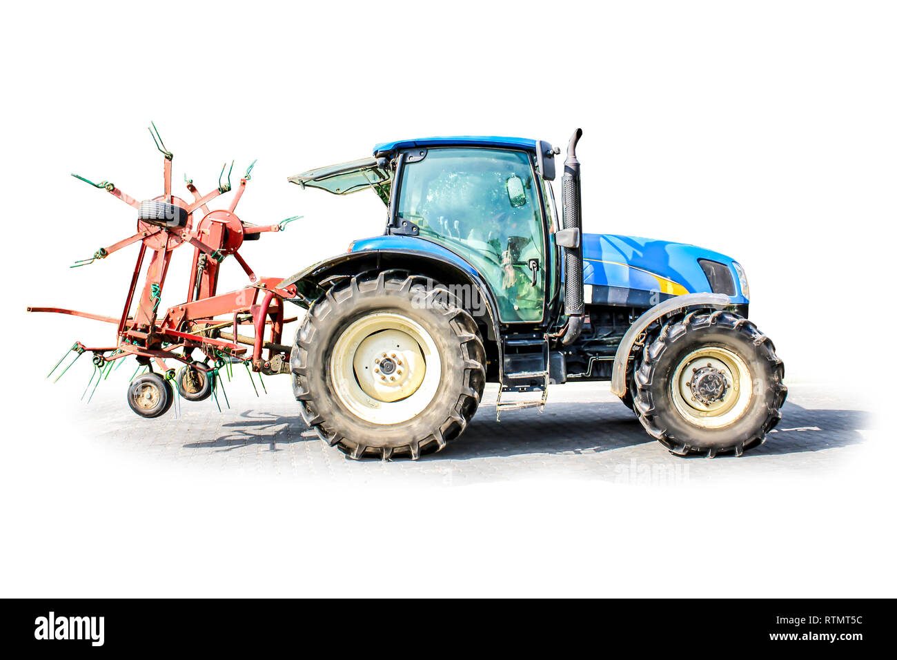 Powerful tractor with a big grass tedder . Isolated photo. Necessary equipment for a dairy farm. Stock Photo