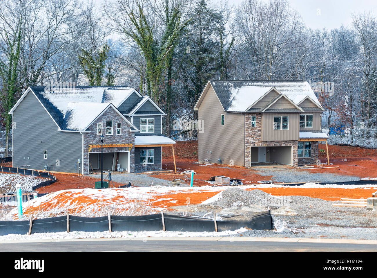 Horizontal shot of two new two-story homes under construction in the winter.  Snow is on the ground and roofs. Stock Photo