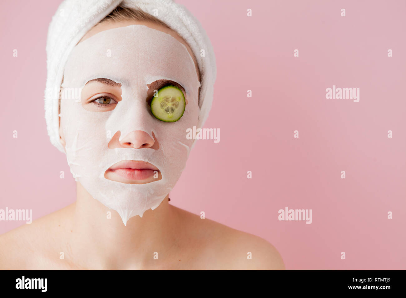 Beautiful young woman is applying a cosmetic tissue mask on a face with