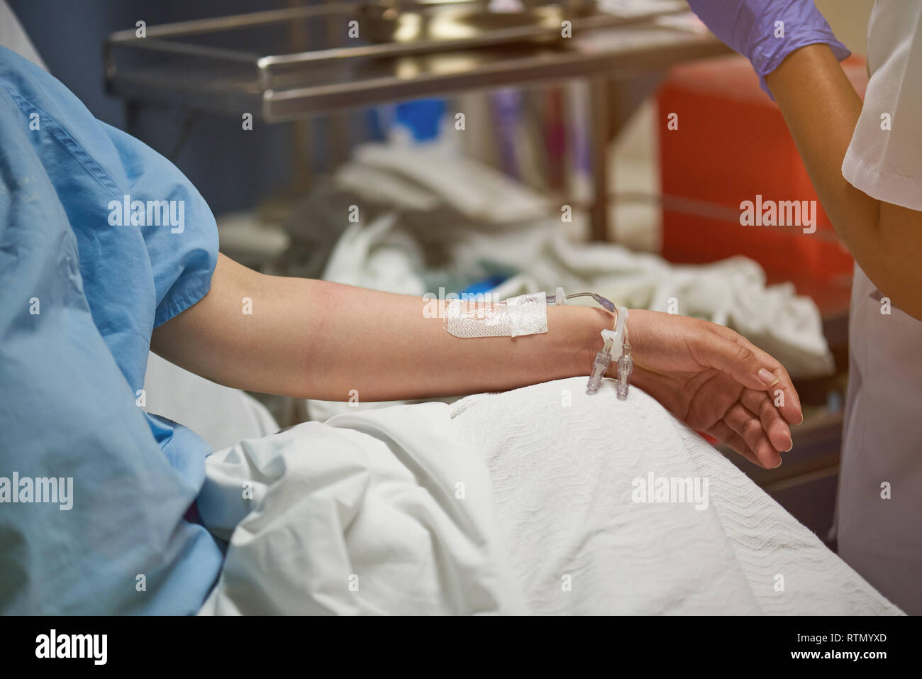 Patient with catheter in arm on hospital blurred room background Stock