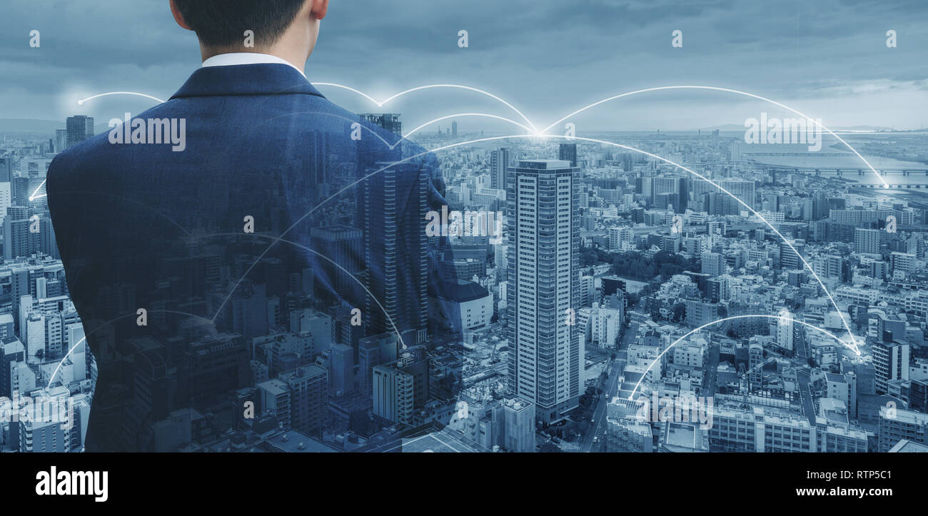 Businessman in blue suit looking at city with network connection in the city. Business network technology, logistics and blockchain business Stock Photo