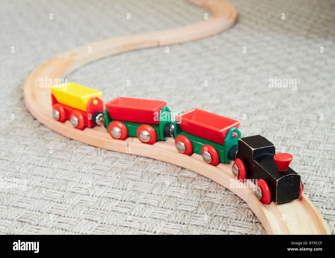 Wooden toy train running on miniature railroad. The black engine