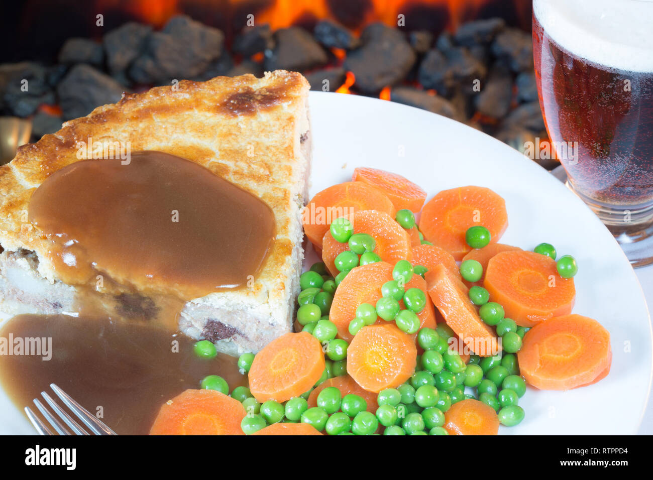 Meat and potato pie with garden peas and carrots served with gravy