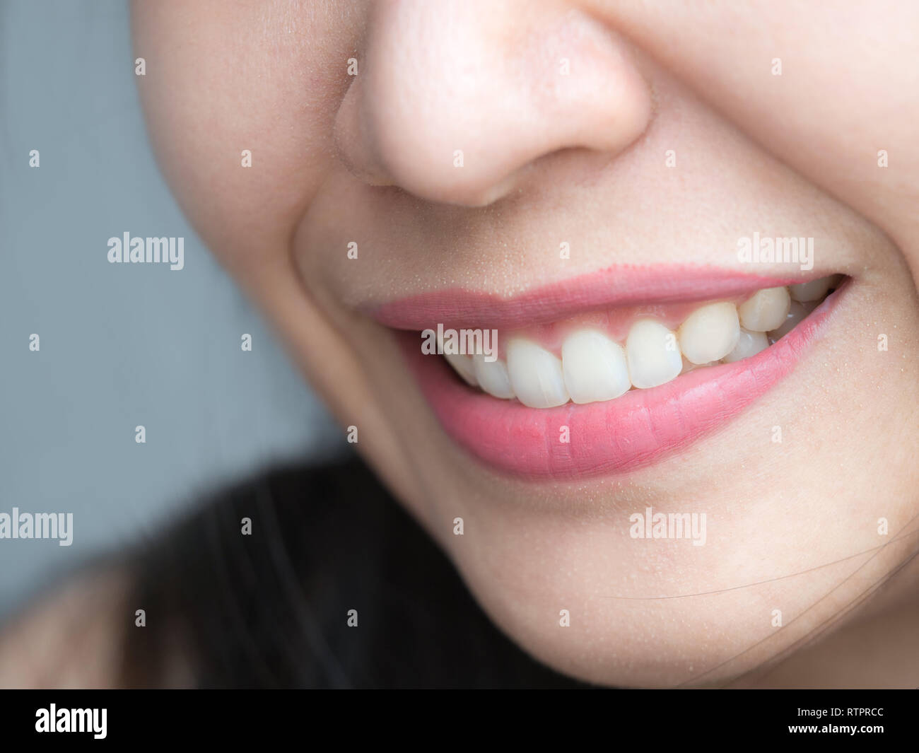 Closeup shot of Asian Chinese Thai woman female makeup face. Woman with red lips lipstick and healthy dental white great perfect teeth. Dental Stock Photo