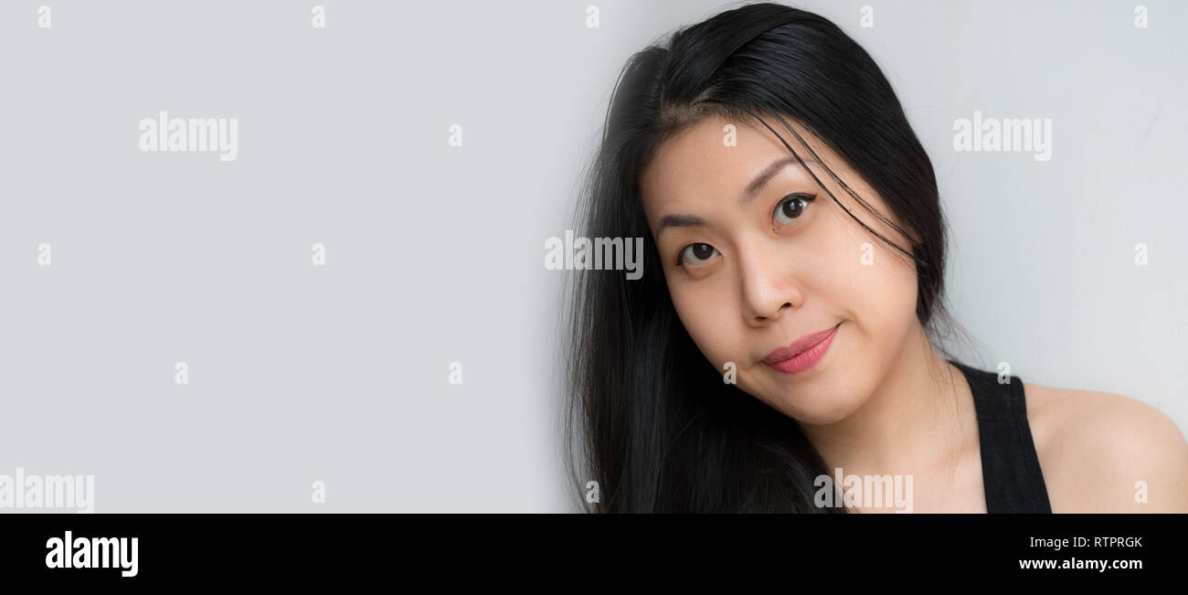 Headshot of Relaxed confident happy Asian Thai Chinese woman smiling with black hair, makeup, happy fresh on white background looking Stock Photo