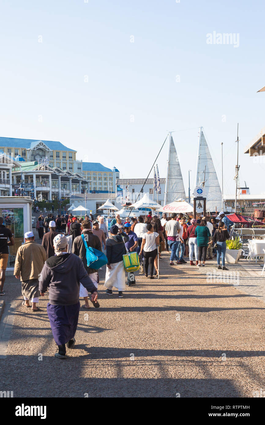 crowd of people or pedestrians walking on a busy sunny Winter day at the V&A Waterfront, Cape Town, South Africa Stock Photo