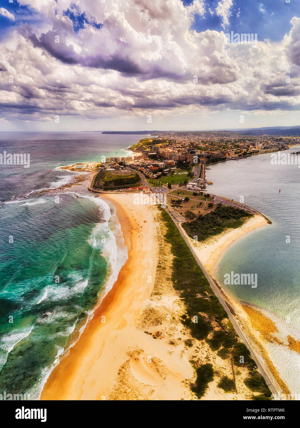 Wide flat Nobbys head sand dunes cape of Newcastle city on Australian pacific coast near delta of Hunter river in aerial vertical panorama view. Stock Photo
