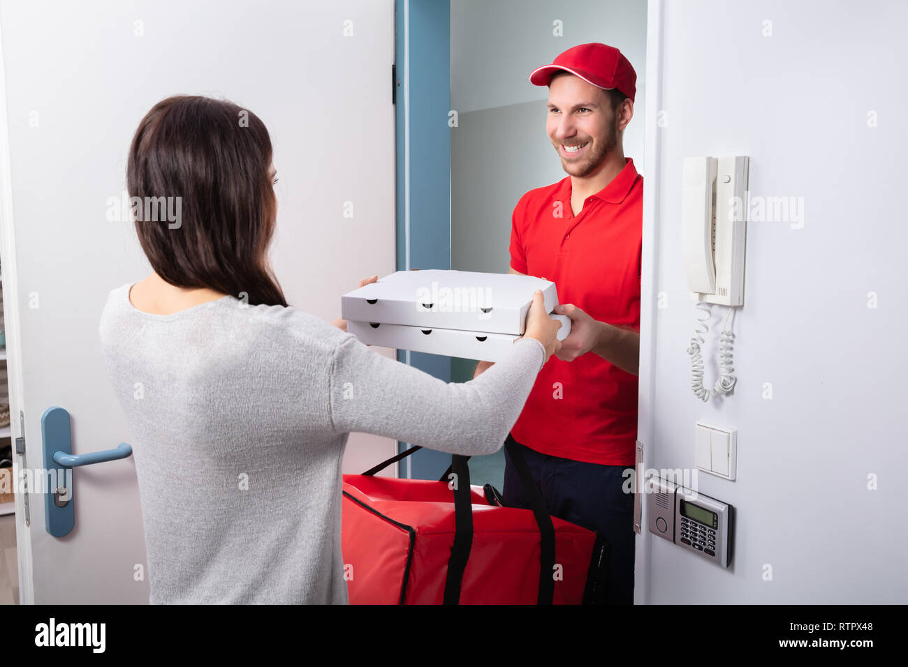 Smiling Woman Receiving Pizza From Delivery Man At Home Stock Photo