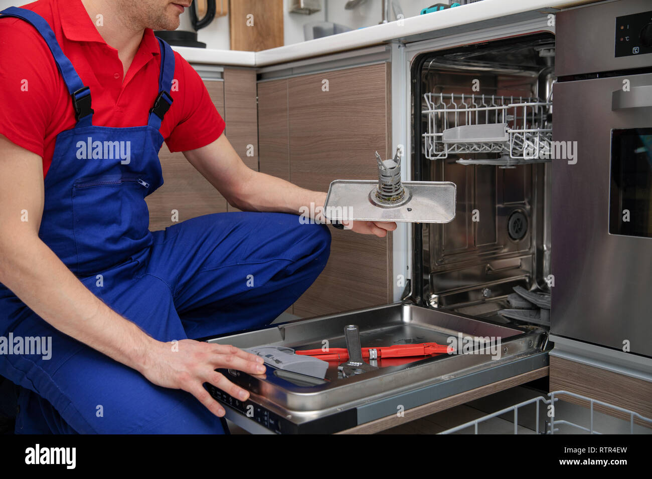 home appliance maintenance - handyman removing dirty dishwasher food residue filter Stock Photo