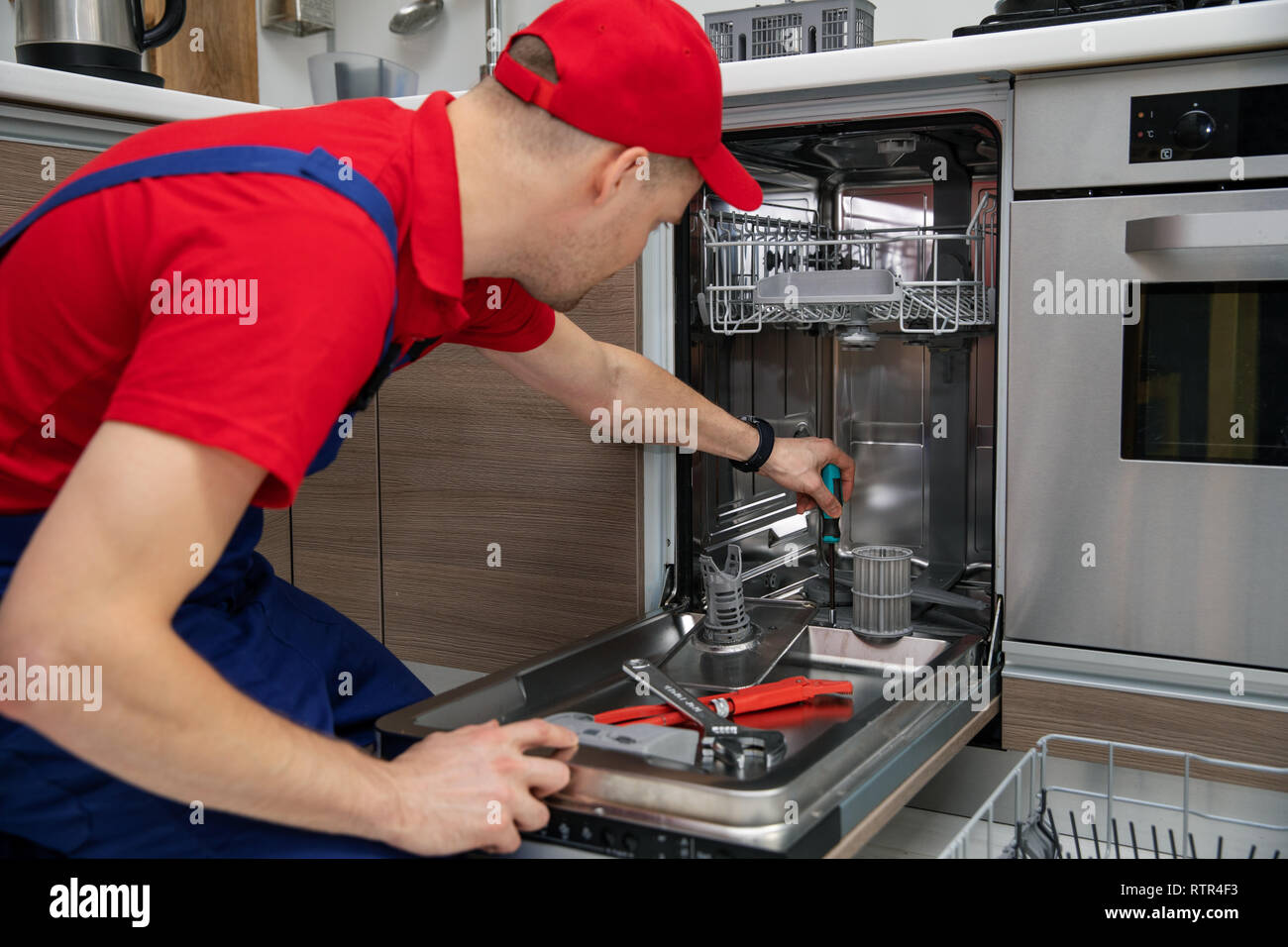 home appliance maintenance - repairman repairing dishwasher in kitchen Stock Photo
