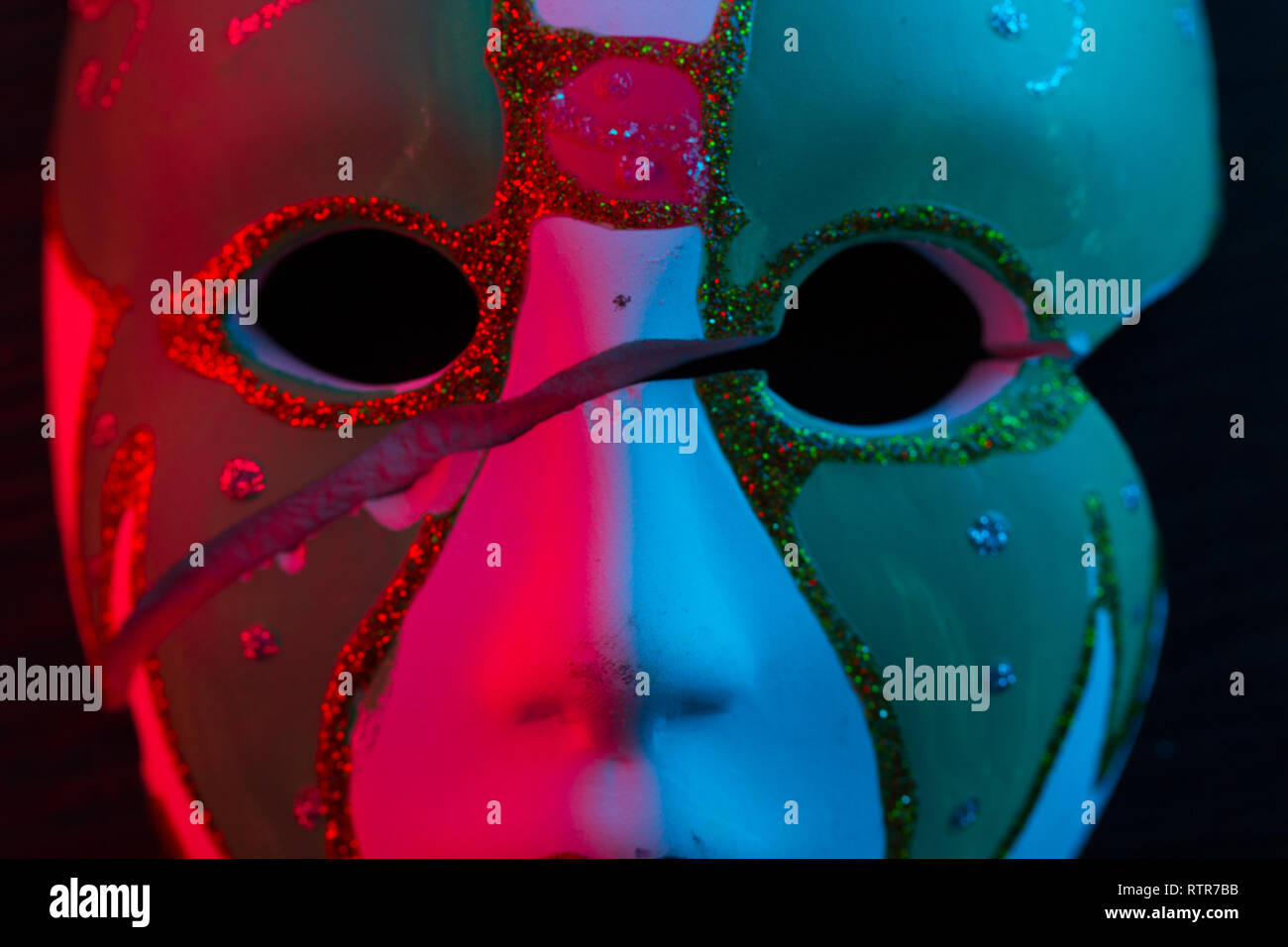 White mask on the dark wall in red light Stock Photo