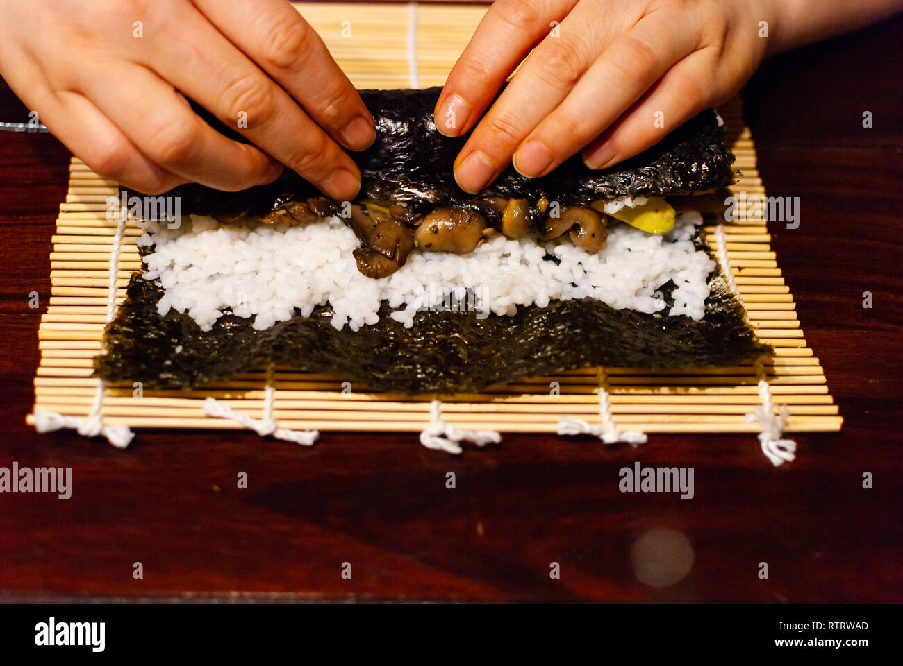 https://c8.alamy.com/comp/RTRWAD/side-view-of-a-young-women-rolling-homemade-vegan-sushi-on-a-wooden-table-RTRWAD.jpg