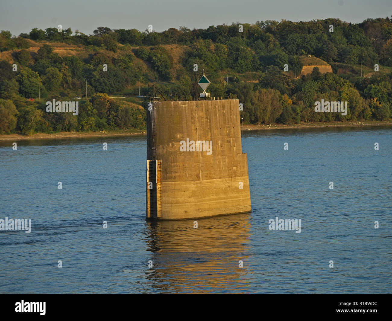 Abandoned old concrete bridge pillar in river with other side behind Stock Photo