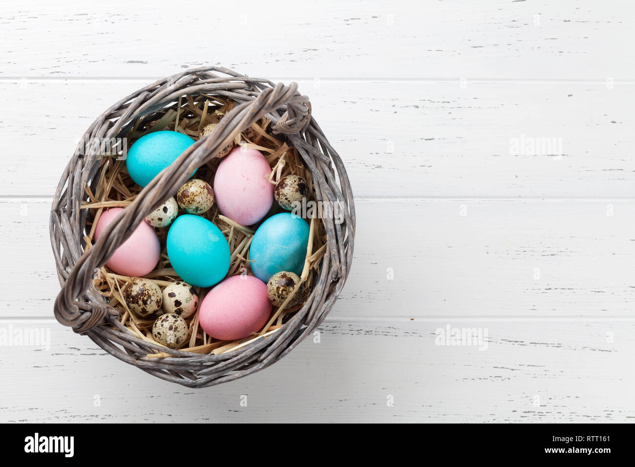 Easter greeting card with colorful eggs in basket on white wooden table ...