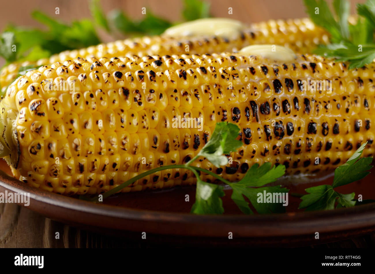 Grilled Sweet Corn Cob With Melting Butter And Greens On Clay Dish ...