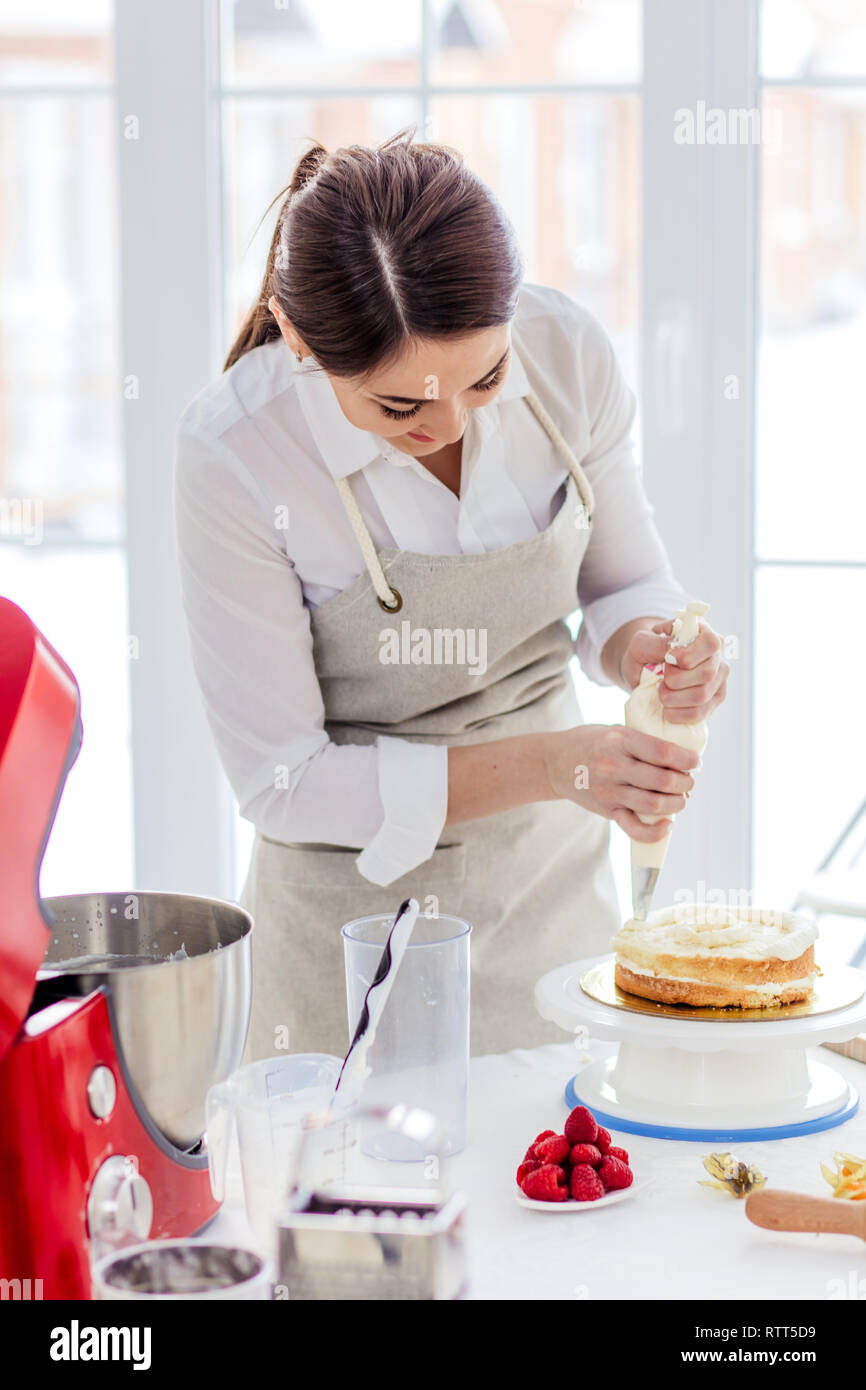 positive female chef decorating cake, close up photo, happy girl