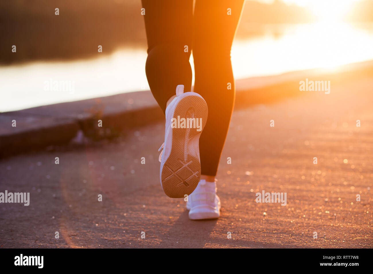 Close up white sneaker of athlete woman runner feet on sunset background Stock Photo