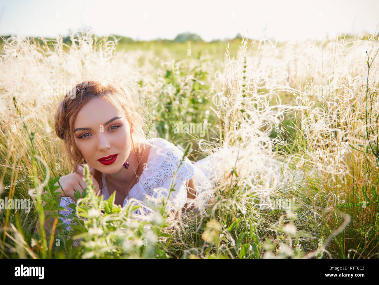 Portrait of attractive young girl lying in a grass Stock Photo - Alamy