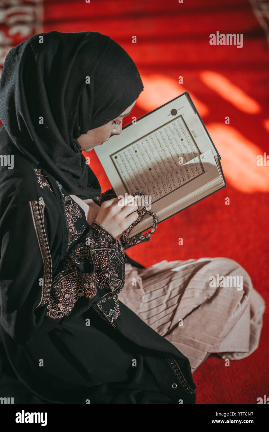 Young beautiful girl reading a holy book of muslim Quran Stock Photo