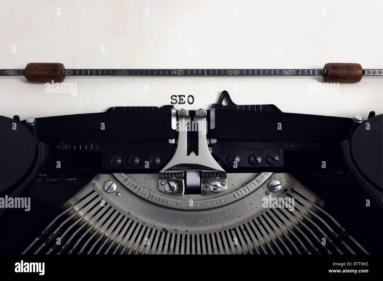 Old retro vintage black typewriter with close-up typing text SEO as heading on aged paper Stock Photo