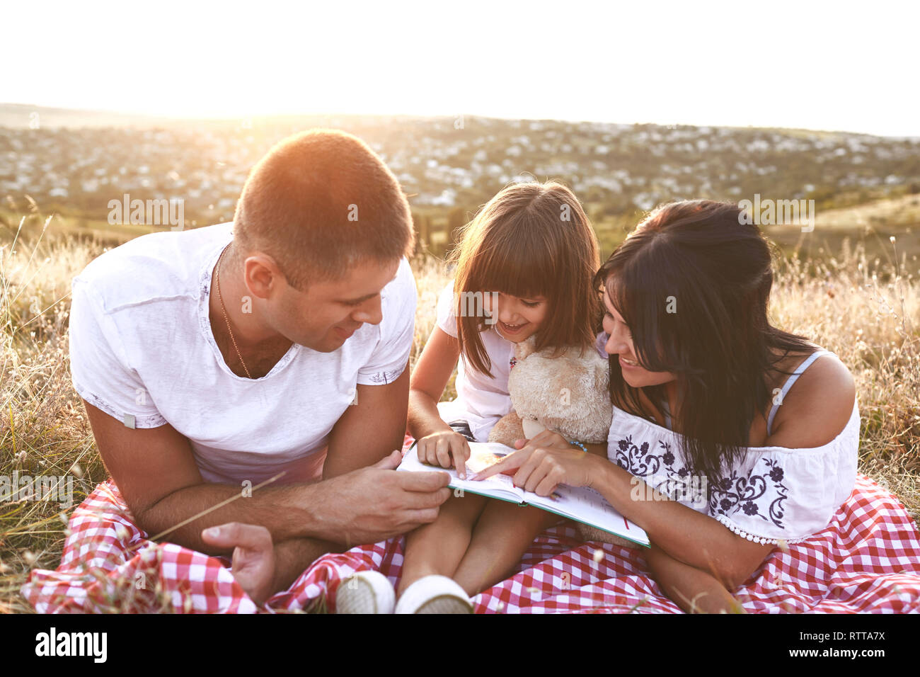 Family is reading a book  in nature. Stock Photo