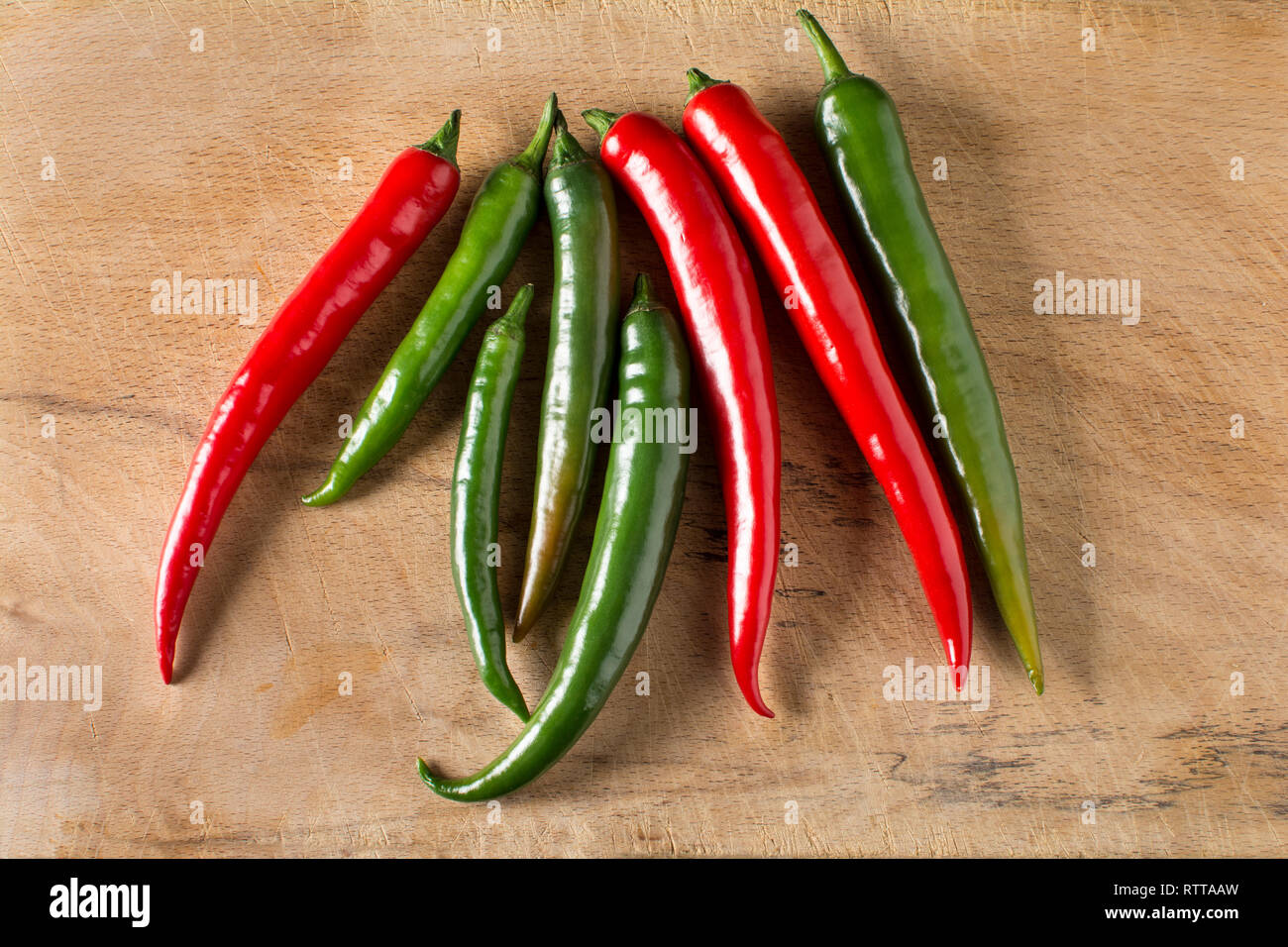 Red and green hot chilli peppers on a carving board with knife Stock Photo