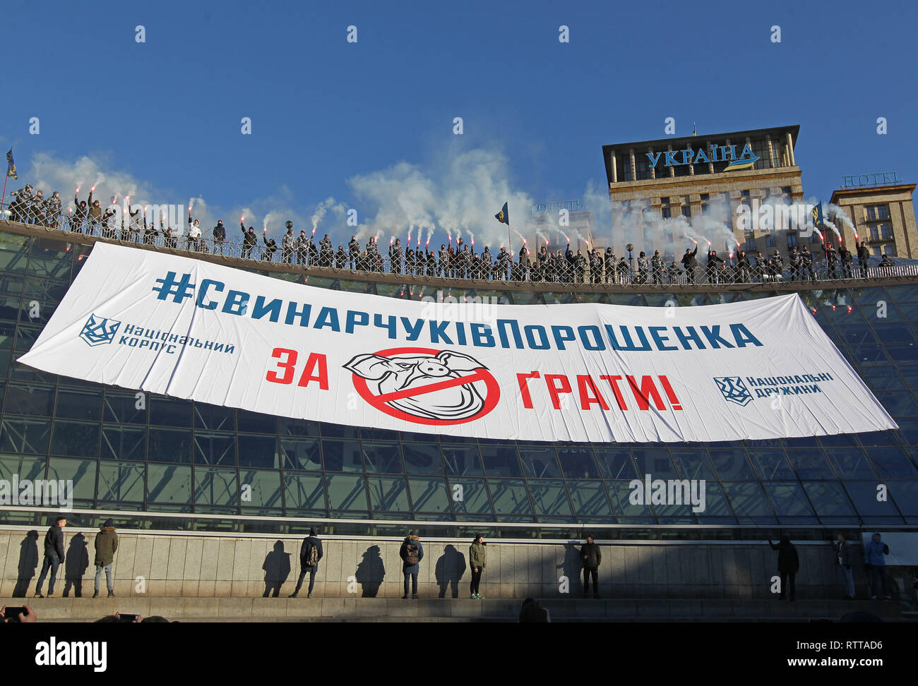 Activists and supporters of 'National Corps' Ukrainian nationalist parties are seen burning flares while holding a banner with the demand to imprison those involved in embezzling budget funds in the defence sector during the protest at the Independence square in Kiev. On February 25 the journalists released the investigative report claiming that Ihor Gladkovsky, the son of First Deputy Secretary of the NSDC Oleh Hladkovsky, is involved in large-scale schemes of embezzling budget funds in the defence sector. Ukrainian President of Ukraine Petro Poroshenko is demanding that law enforcement agenc Stock Photo