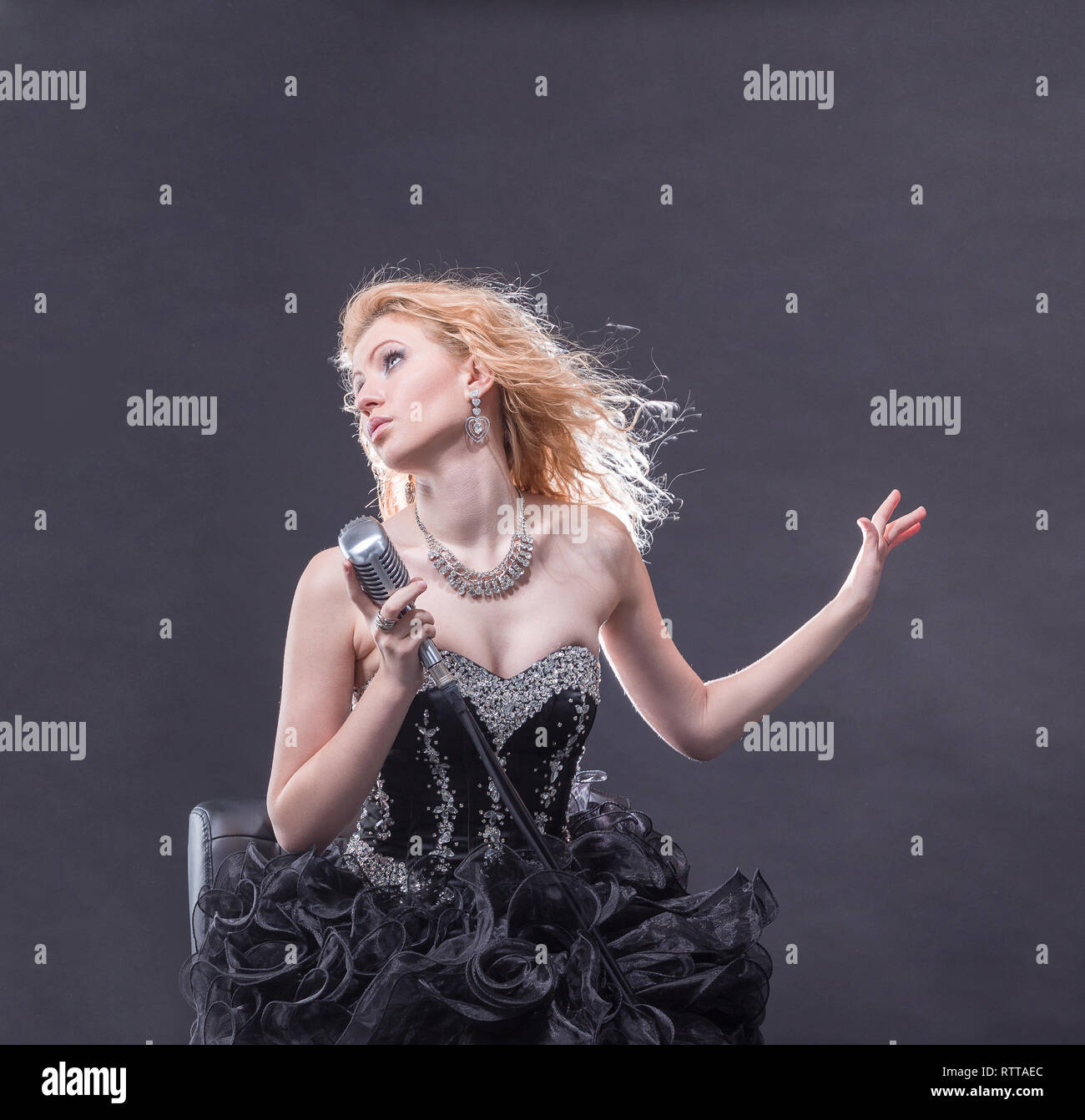 beautiful girl singer performing a song sitting on a chair Stock Photo