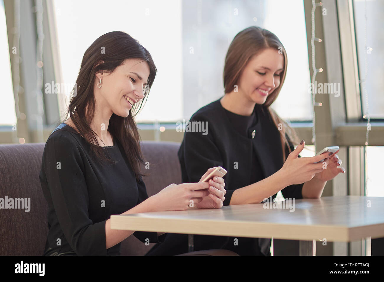 employees using their smartphones sitting at a table in a cafe Stock Photo