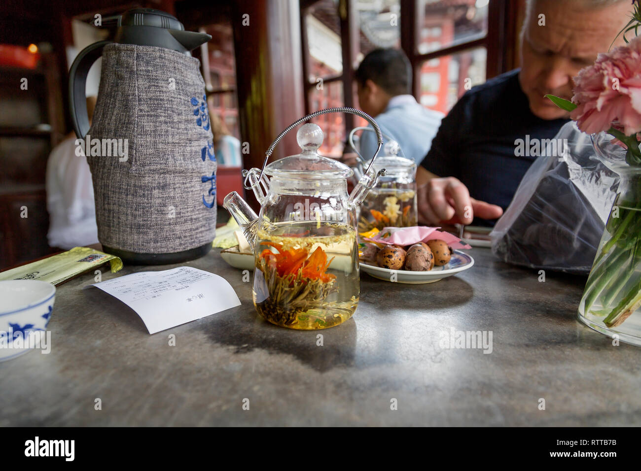 A customer enjoys a traditional Chinese tea and quail eggs at Huxinting Teahouse one of the most famous tea houses in China. Yu Garden, Old Shanghai. Stock Photo
