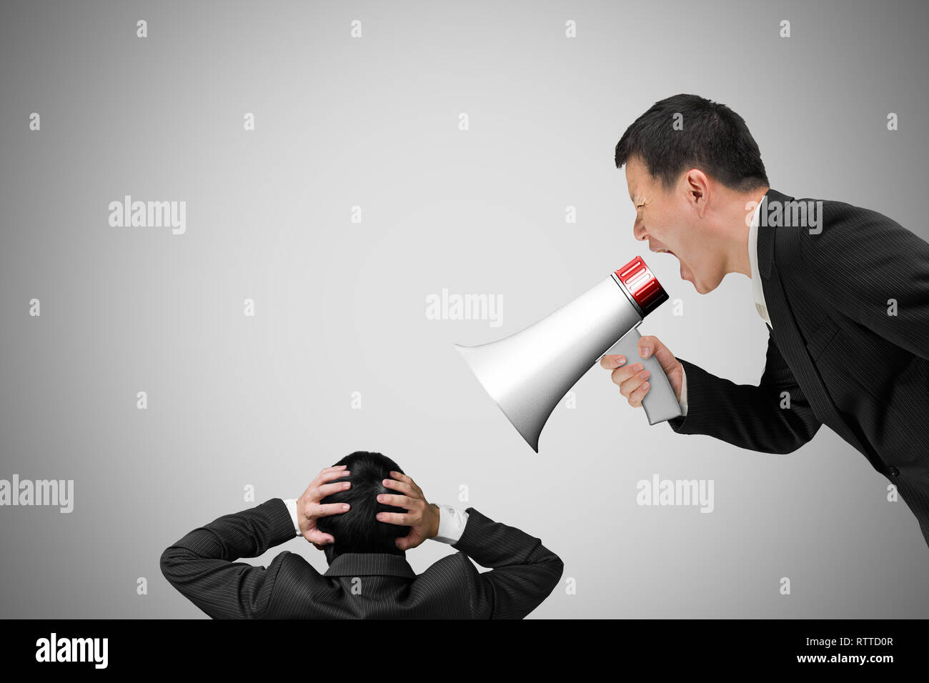 Boss using megaphone yelling at his employee with concrete wall background Stock Photo