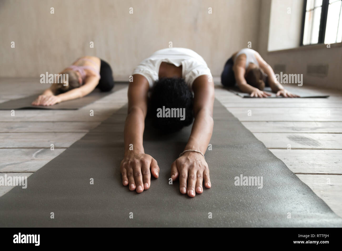 Black yogi woman and group of people doing Balasana exercise Stock Photo