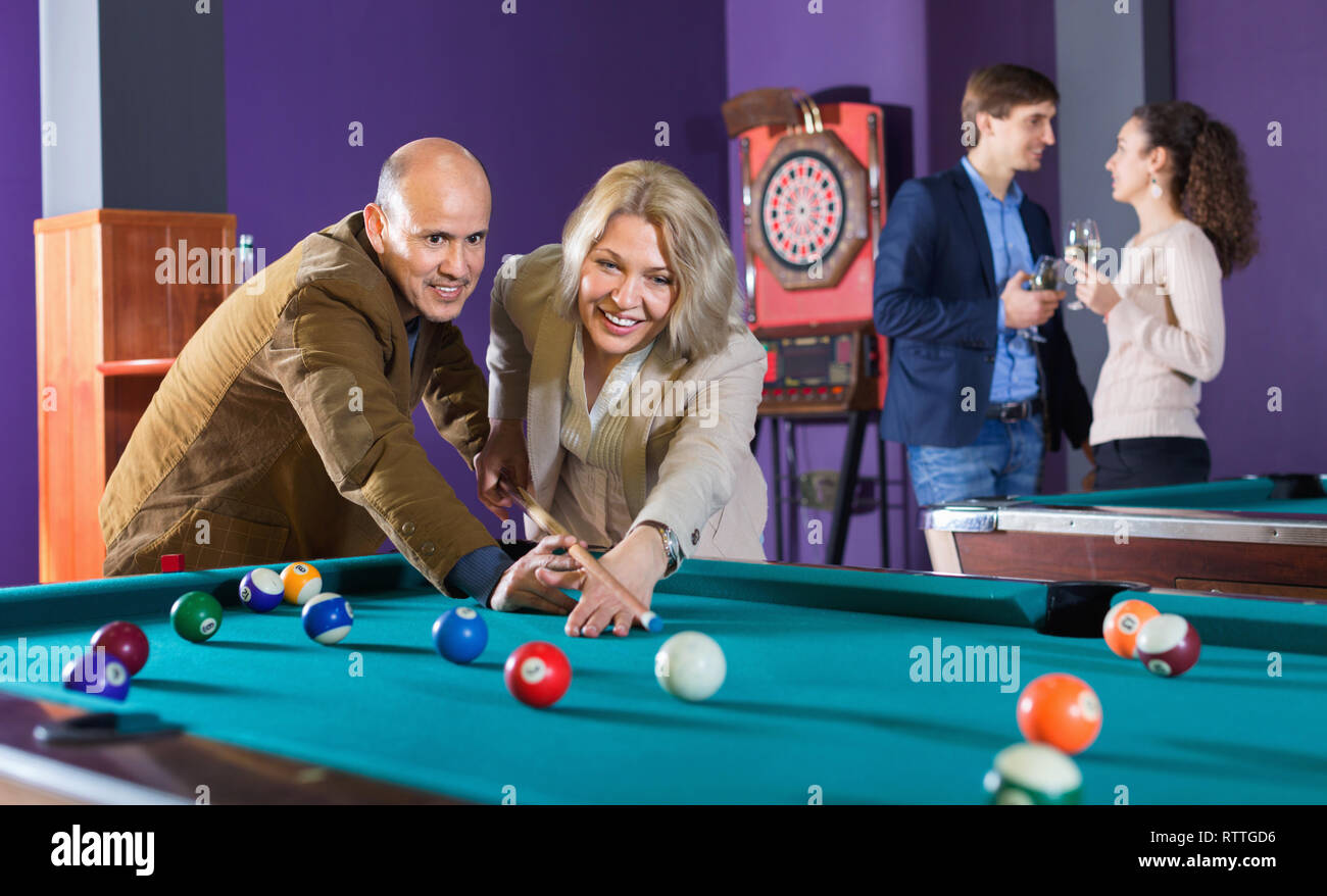Relaxed happy people playing billiard and darts as hanging out Stock