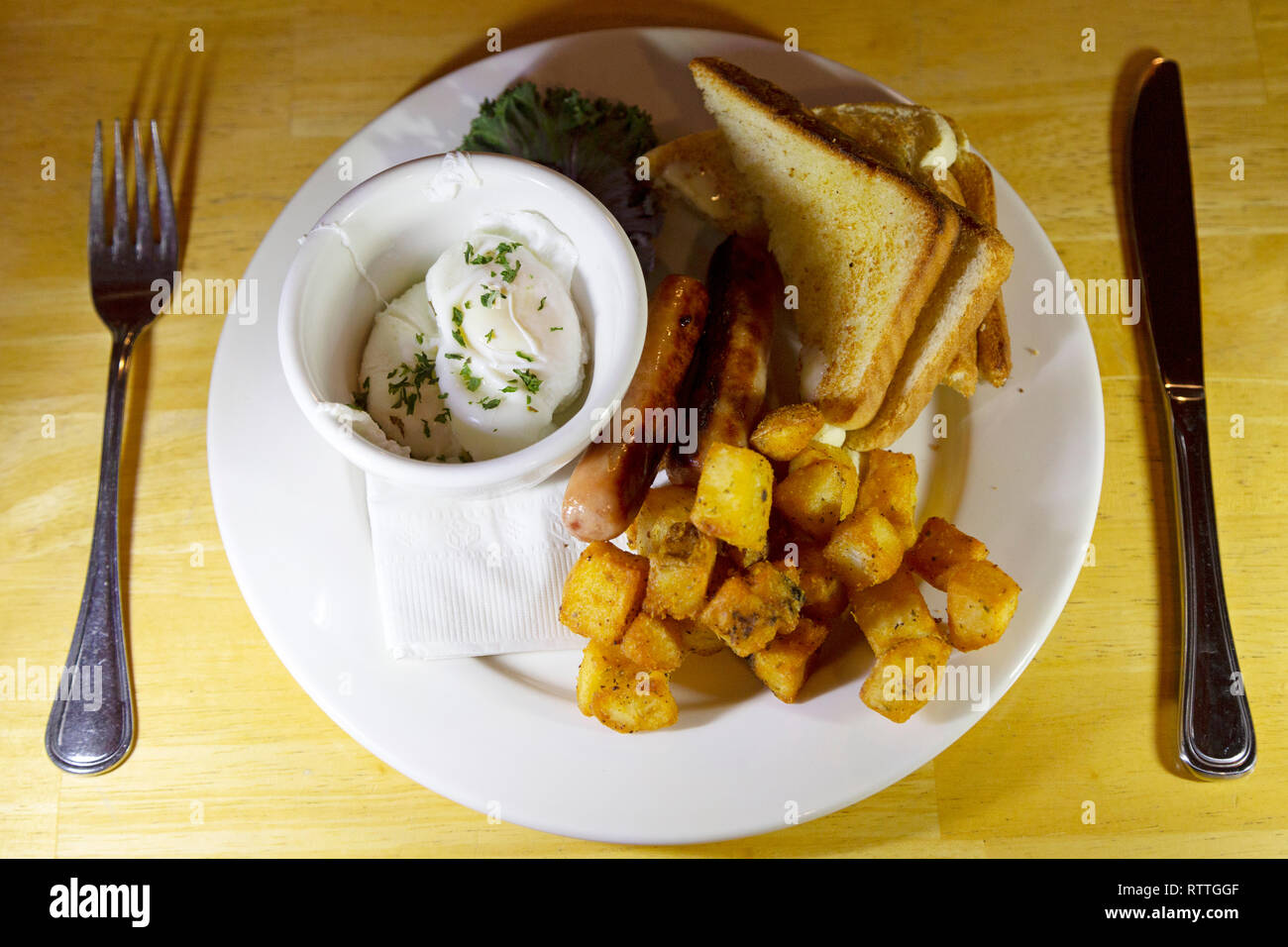 A Canadian breakfast served in Manitoba, Canada. It features sausages, a poached egg, toast and hash potatoes. Stock Photo