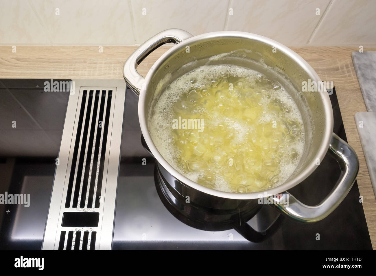 Potatoes in boiling water in a cooking pot on a induction stove Stock