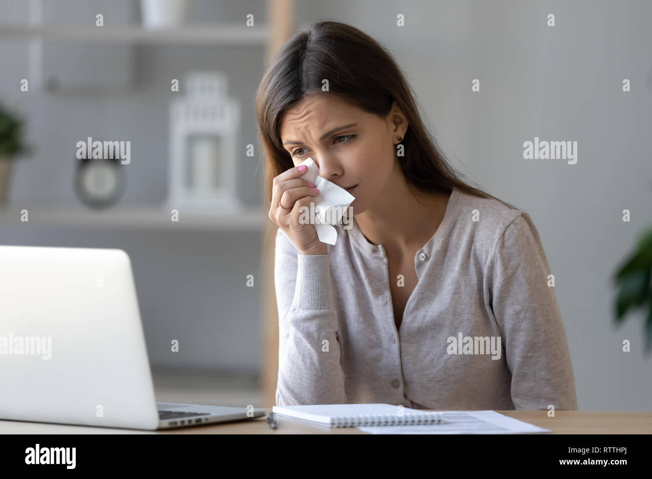Upset woman crying, looking at laptop screen, watching sad movie Stock Photo