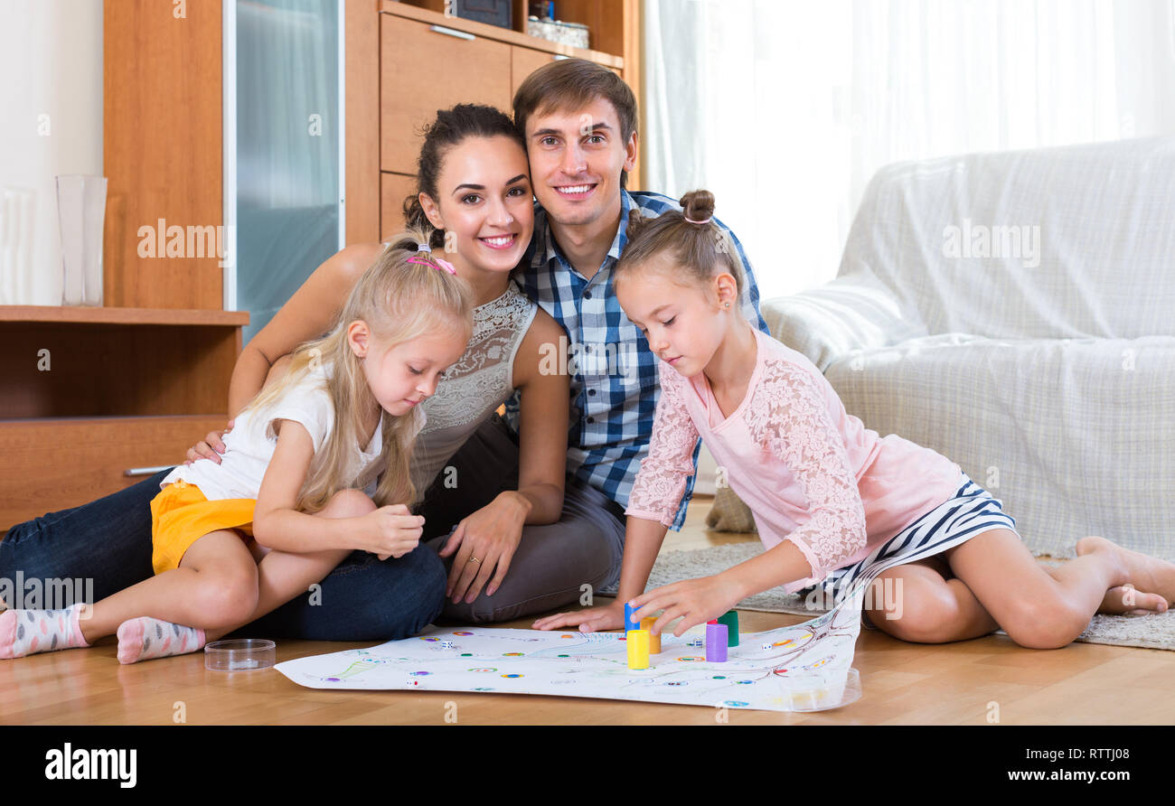 Cheerful parents and two daughters with board game at home Stock Photo