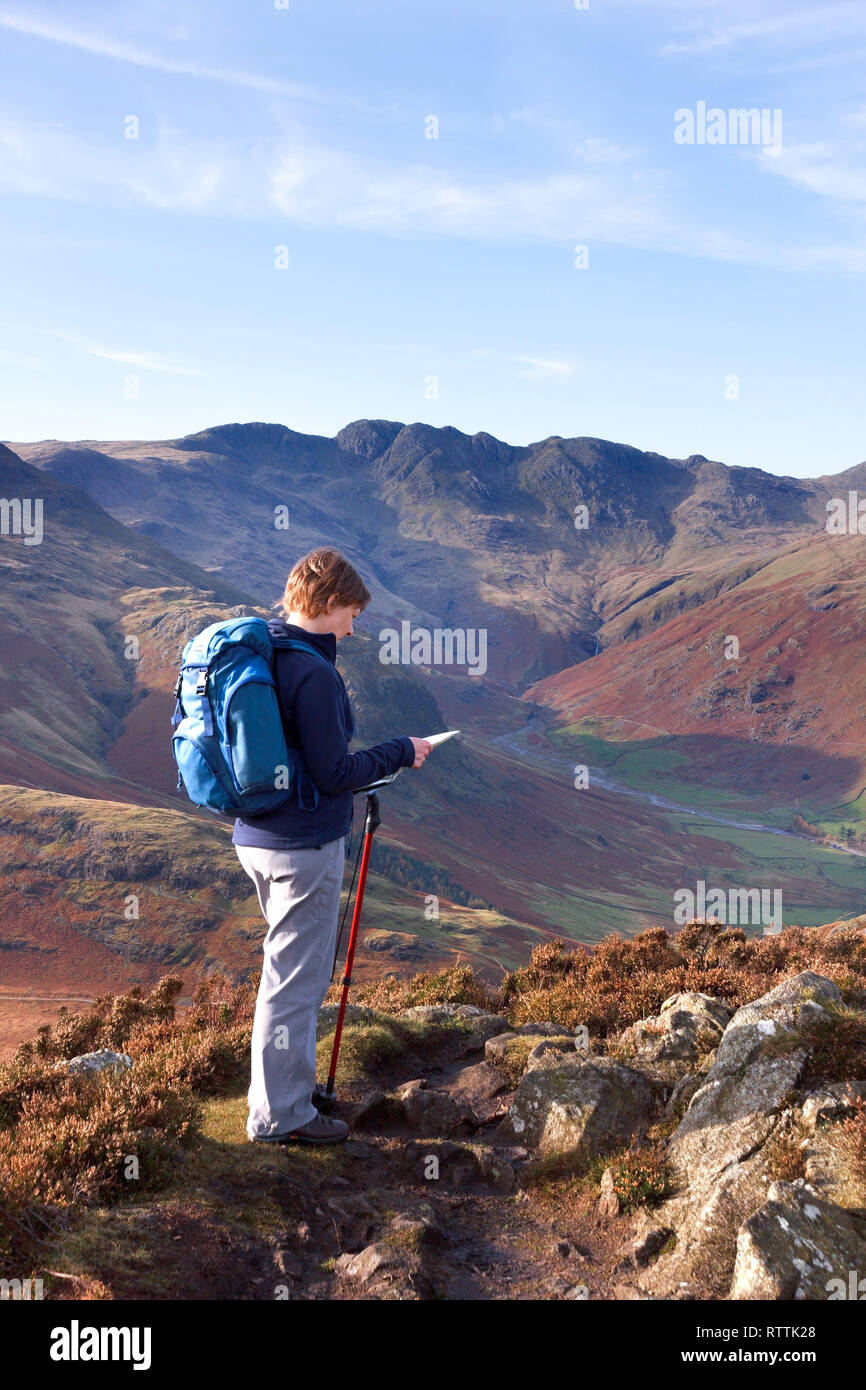 Female hill walker map reading on Side Pike with Oxendale and Crinkle Crags in the distance, Langdale,Lake District, England, UK Stock Photo