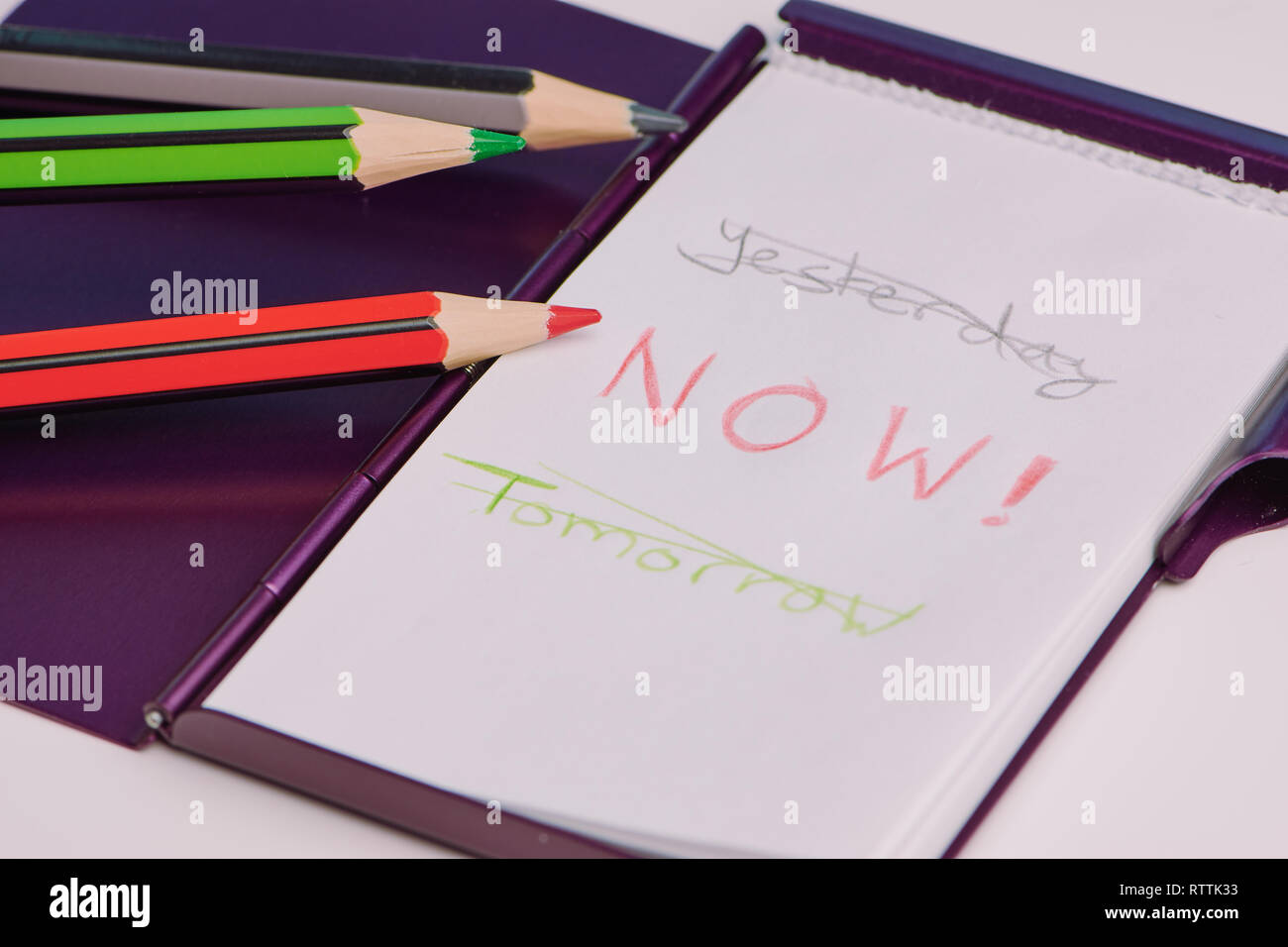 handwritten text with the words: yesterday, now and tomorrow on a white notepad as a concept to live in the moment Stock Photo