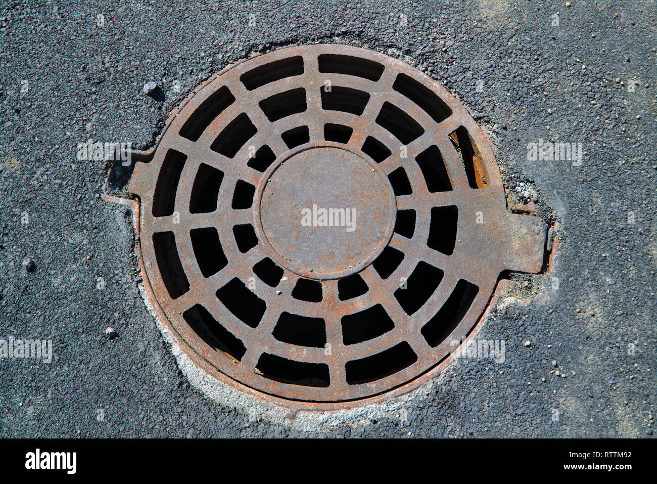 Cast-iron manhole cover storm sewer in the park close-up Stock Photo